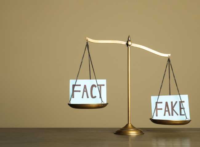 Scale balancing between the words 'Fact' and 'Fake.
